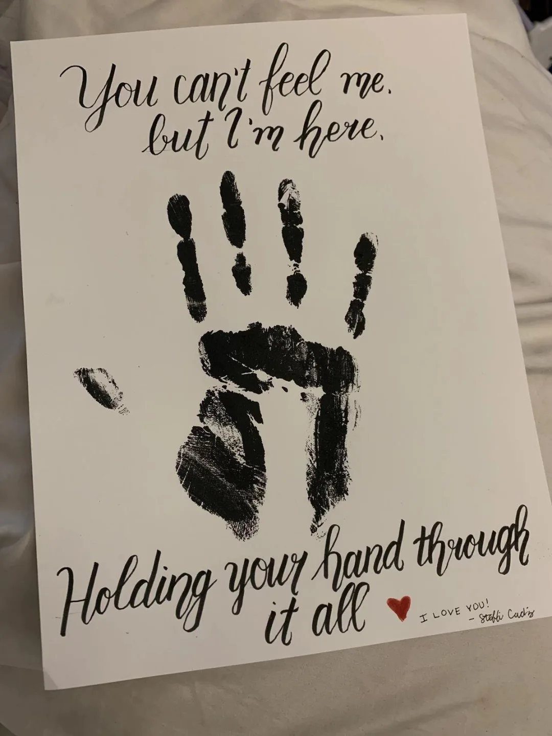 Handprint art on white paper with romantic cursive text and a red heart.