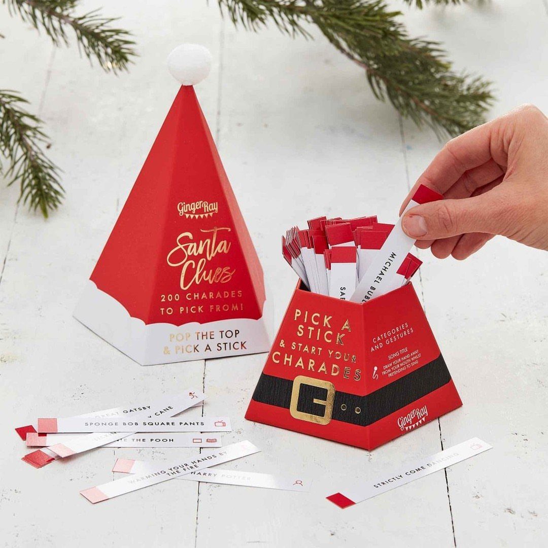 Hand picking a prompt stick from a Santa-themed Christmas charades game box.