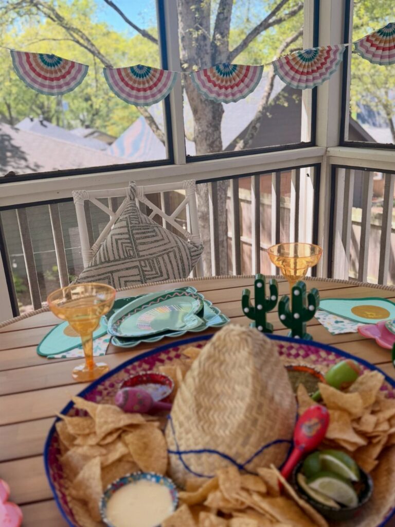 Festive table setting with cactus-shaped turquoise napkins, plates, and a platter of chips.