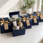 Navy blue gift boxes with gold ribbons containing coffee and honey treats.