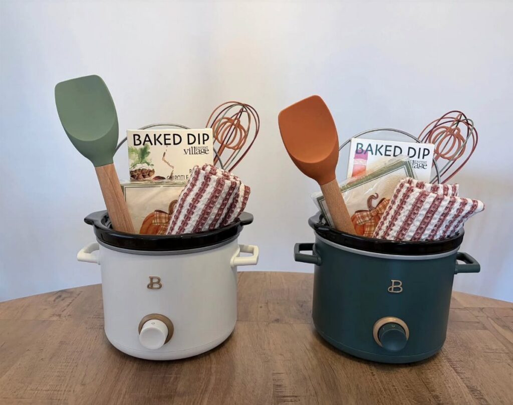 Two slow cookers filled with cooking utensils, recipe books, and checkered napkins.
