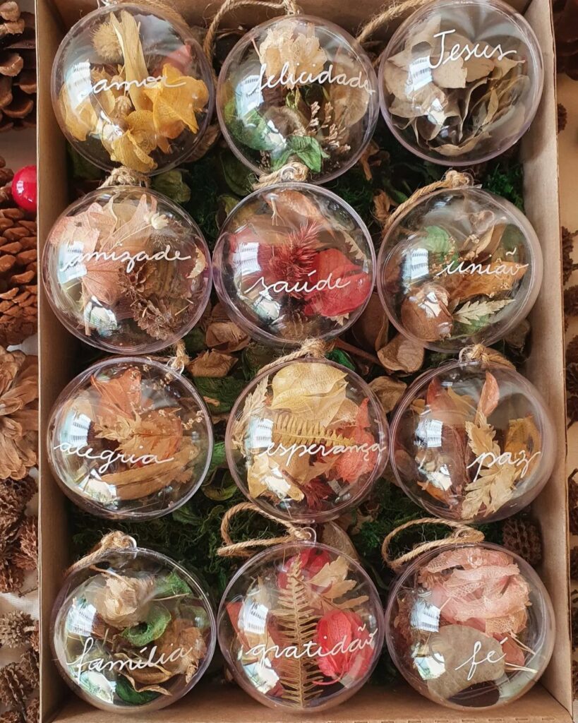 Clear spherical ornaments filled with dried leaves and handwritten words in a box.