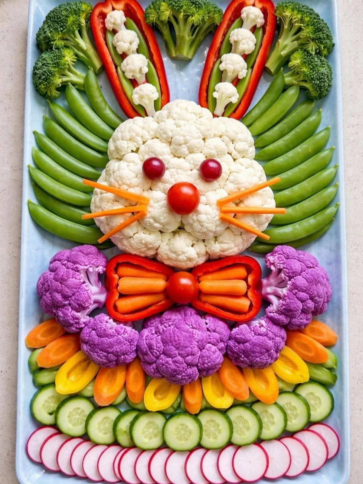 Vegetable tray arranged as a bunny using cauliflower, carrots, peppers, and snap peas.