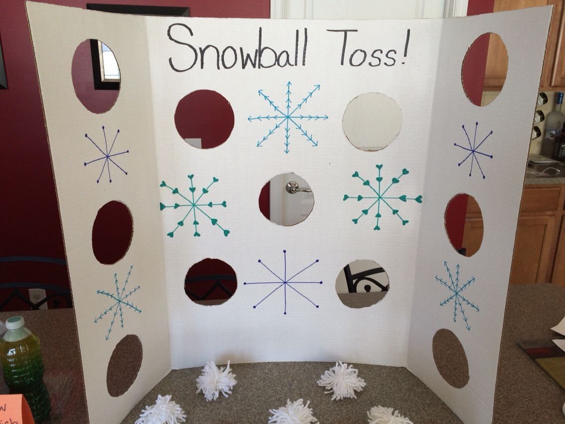 Snowball Toss game board with circular holes and white yarn snowballs on a table