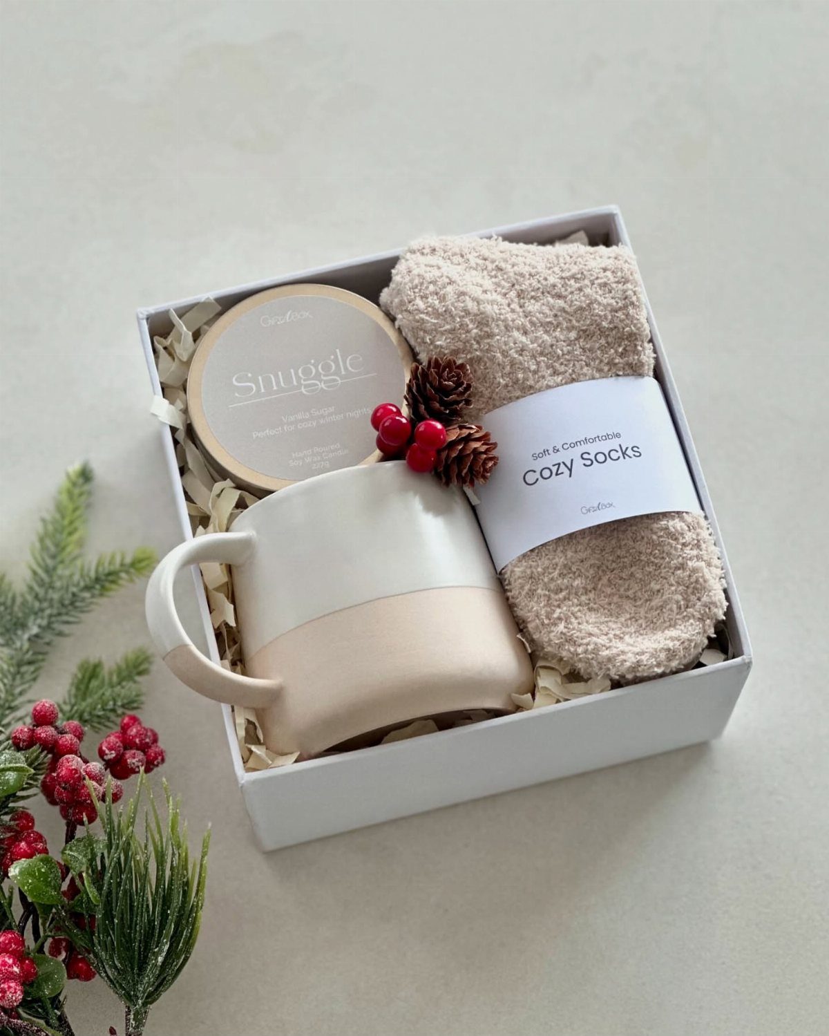 Gift set in a white box with a mug, fuzzy socks, and a candle.