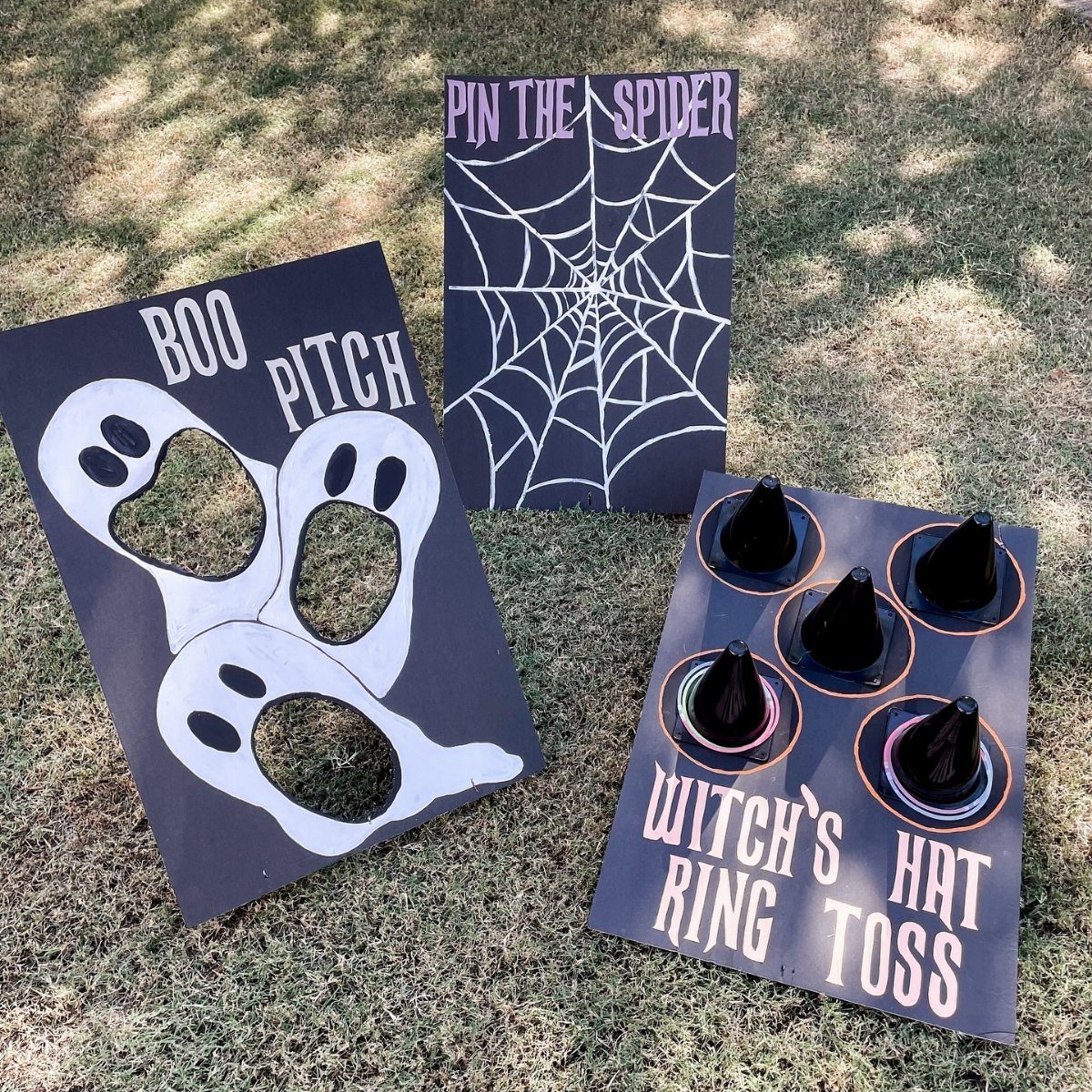 Witch's hat ring toss game board alongside other Halloween carnival games on grass.
