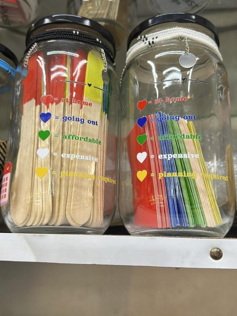Two glass jars filled with colorful popsicle sticks and a date night key.