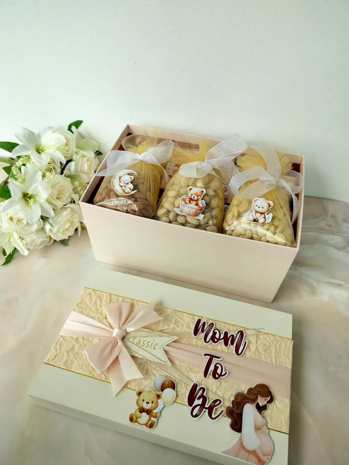 Pink gift box for mom to be with treats and white flowers