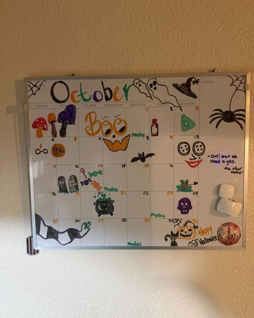 White board October calendar with colorful hand-drawn Halloween doodles and drawings on a wall
